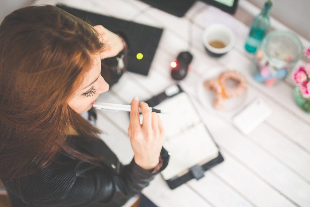 young woman thinking with pen while working studying at her desk